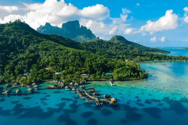 Aerial drone view of overwater bungalows in coral reef lagoon