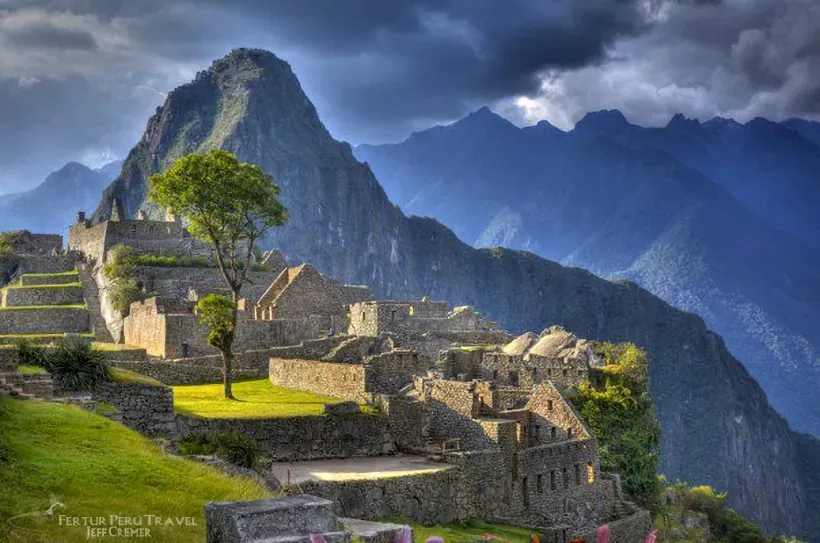 Machu Picchu stone terraces under dark clouds with Huayna Picchu mountain behind