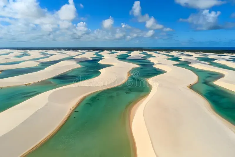 Aerial view of vast white sand dunes with turquoise water at Lençóis Maranhenses