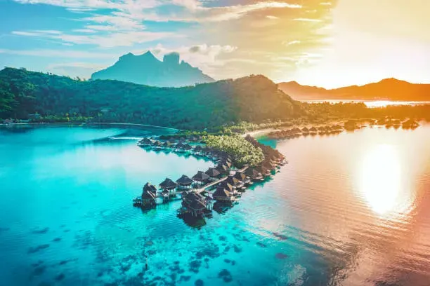 Overwater bungalows at sunset with coral reef visible in golden Bora Bora lagoon waters