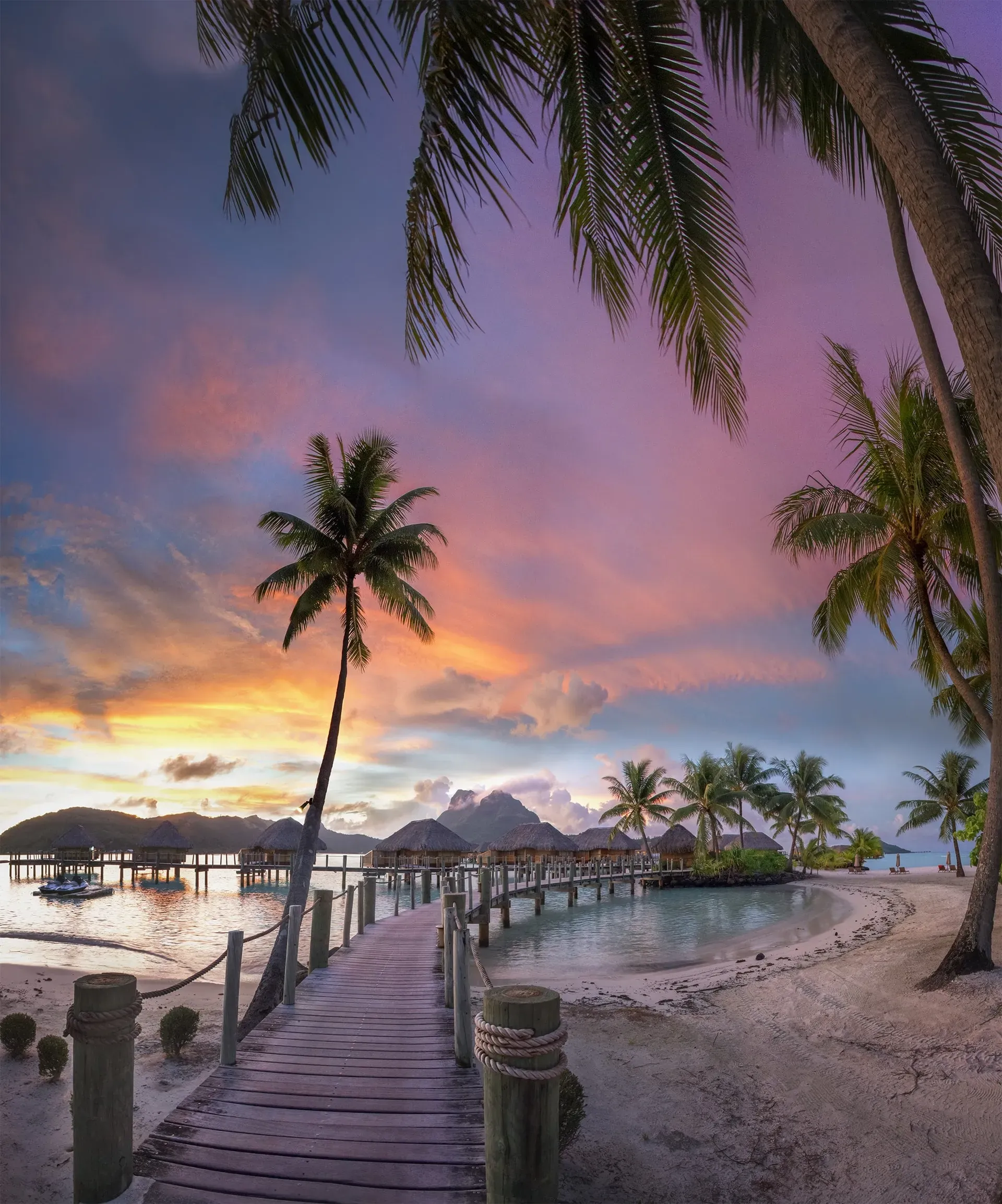 Wooden pier over turquoise water toward Bora Bora overwater bungalows with Mount Otemanu