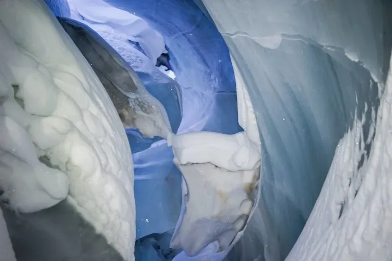 Deep tunnel of glistening blue and white ice within Svalbard ice caves