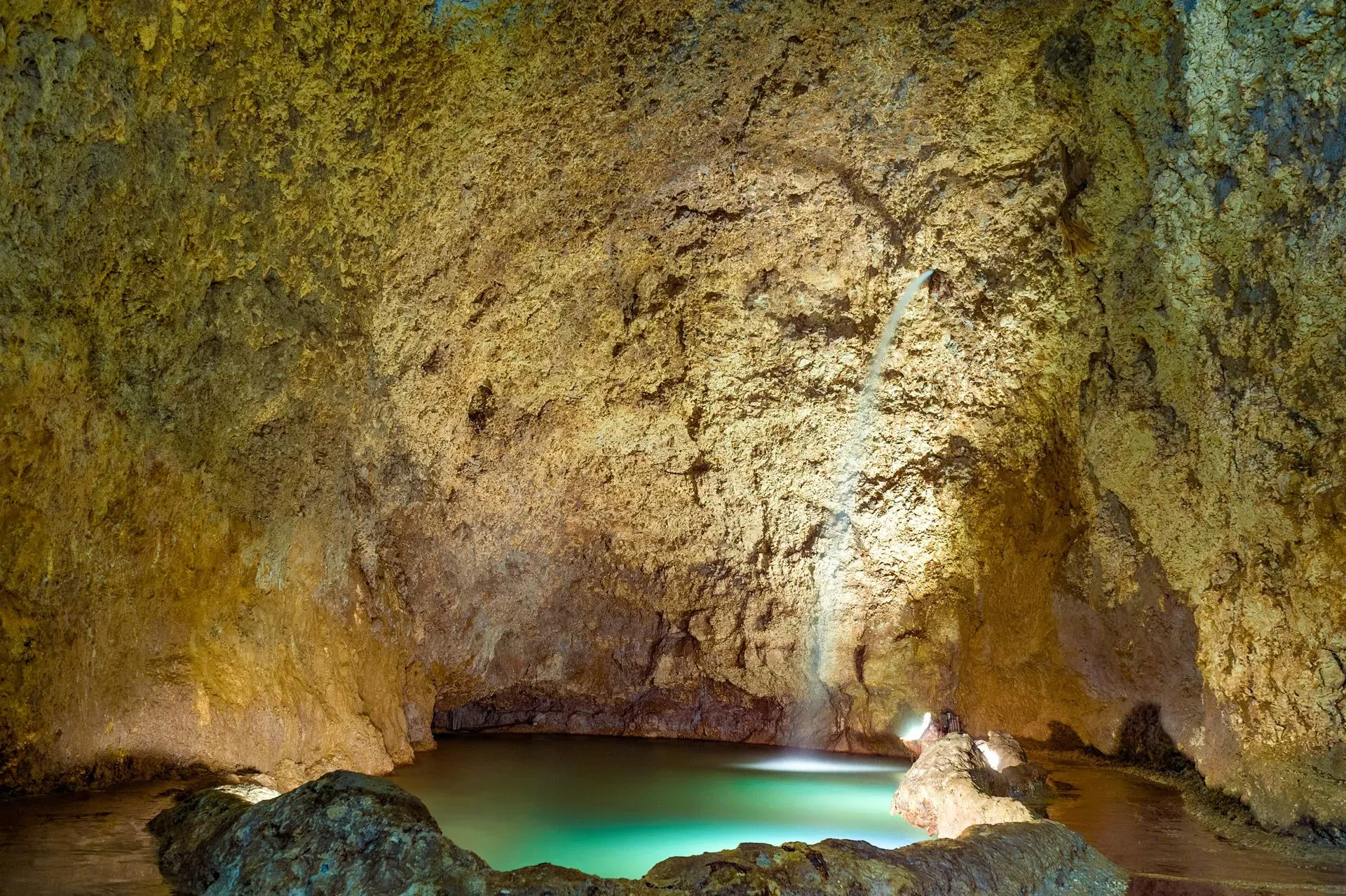 Small waterfall cascading into pool inside limestone cavern