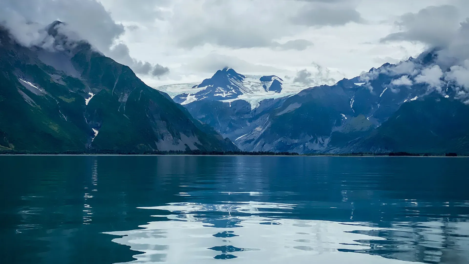 Calm ocean water reflecting mountains and glaciers in Kenai Fjords Alaska