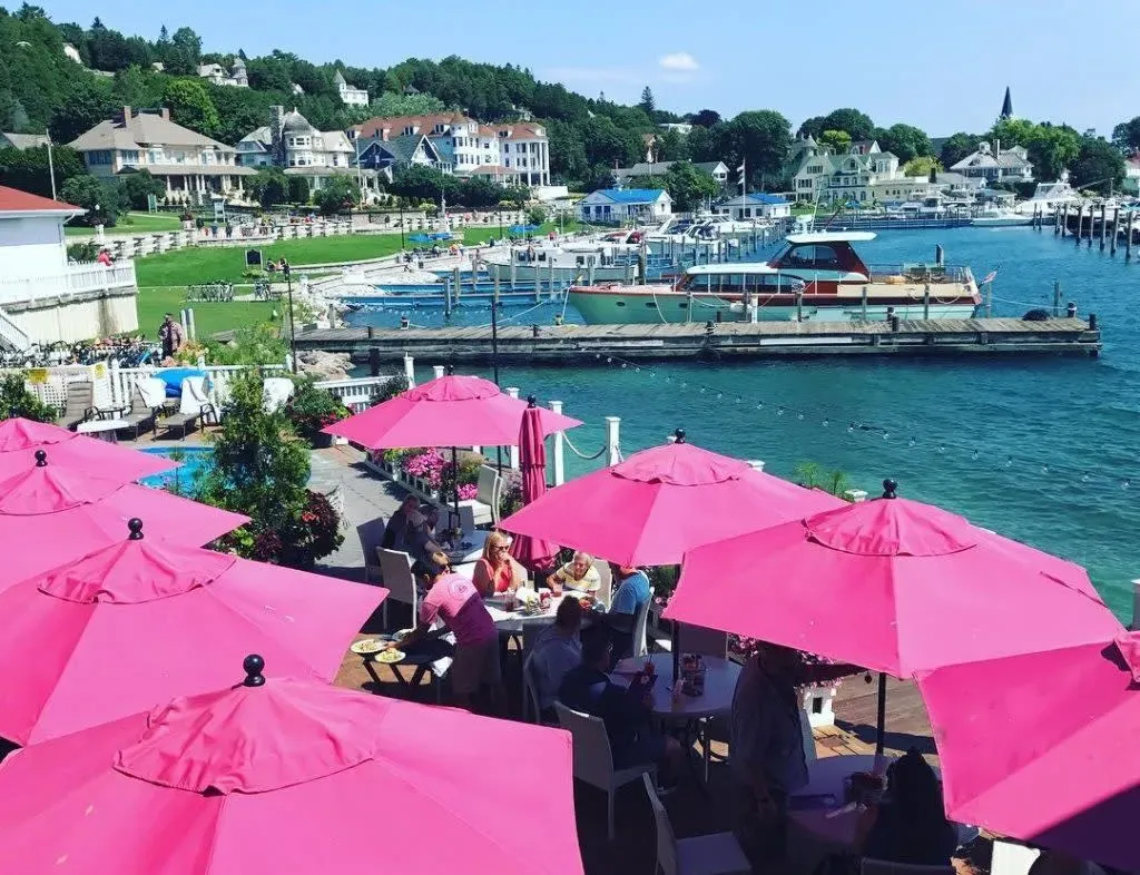 Colorful pink umbrellas shade outdoor waterfront dining overlooking a marina