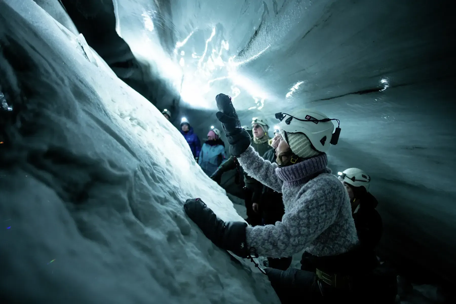 Explorers wearing helmets and winter gear inside the Longyearbreen glacier ice cave