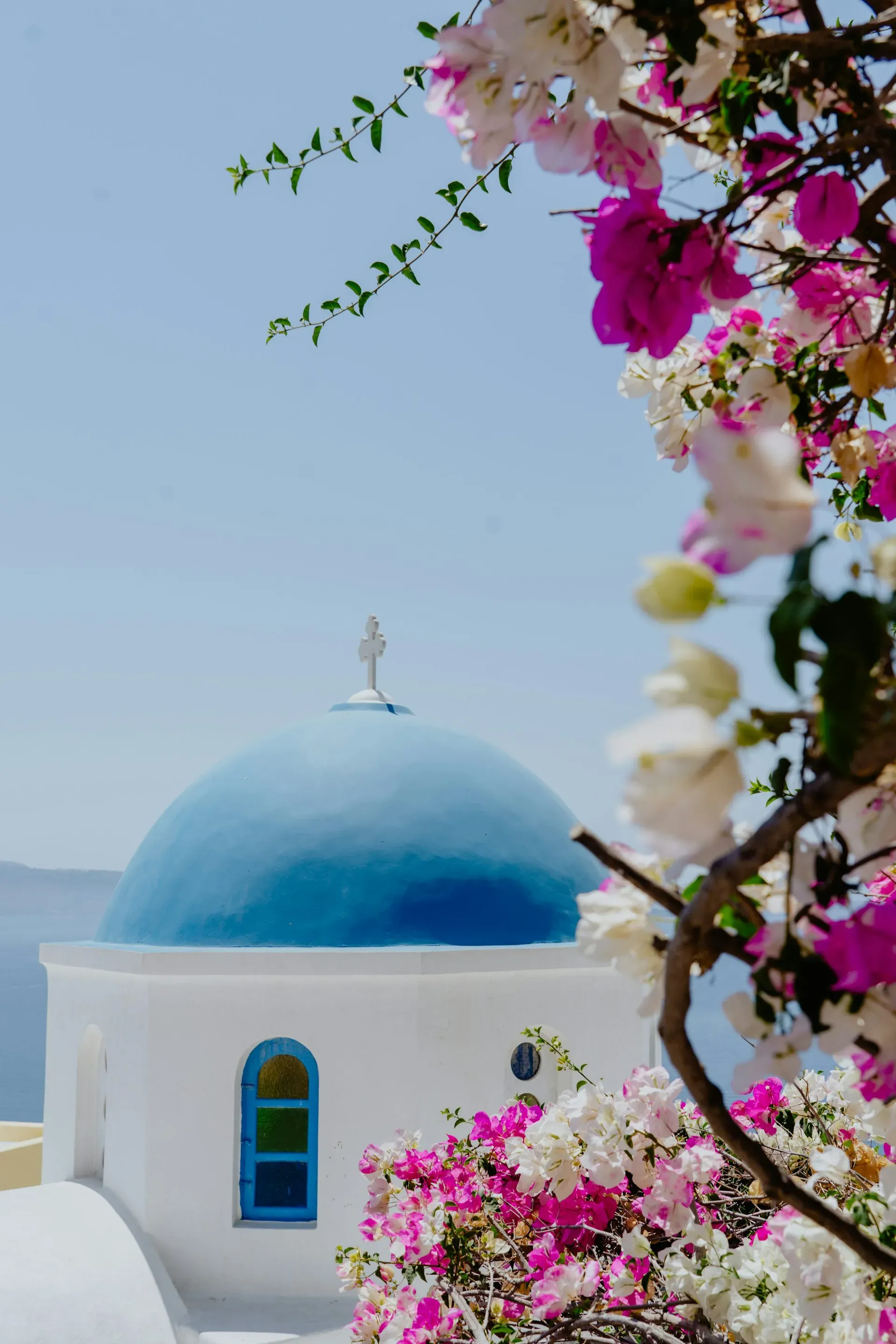 Famous blue domed Greek Orthodox chapel with bell tower on caldera edge