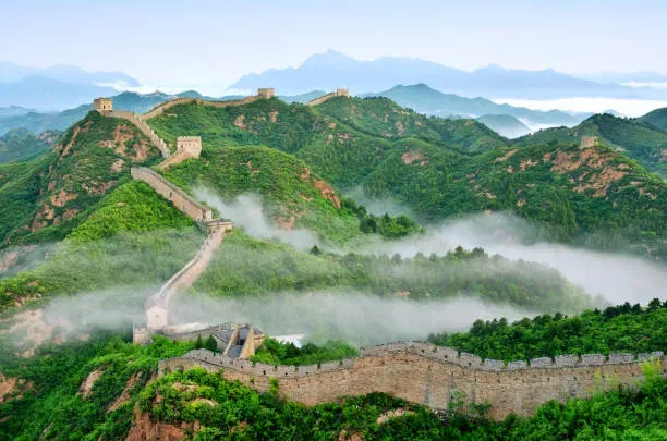 Great Wall of China shrouded in morning fog and mist rising from valleys