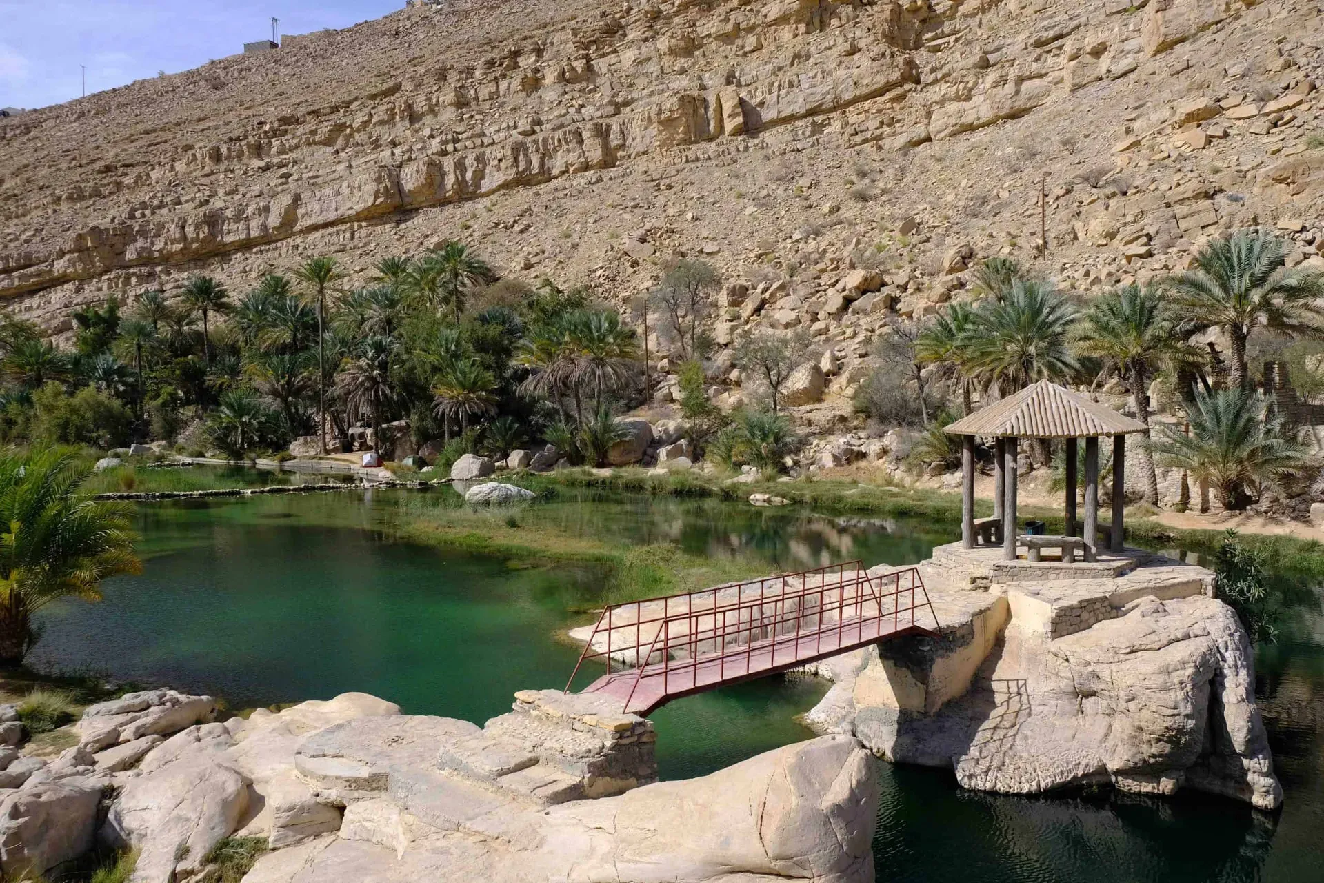 Main pool at Wadi Bani Khalid with wooden bridge and shaded canopy