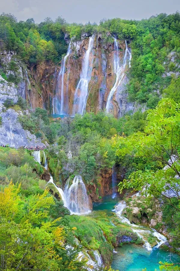 Multiple waterfalls cascading down green cliffs into turquoise lakes