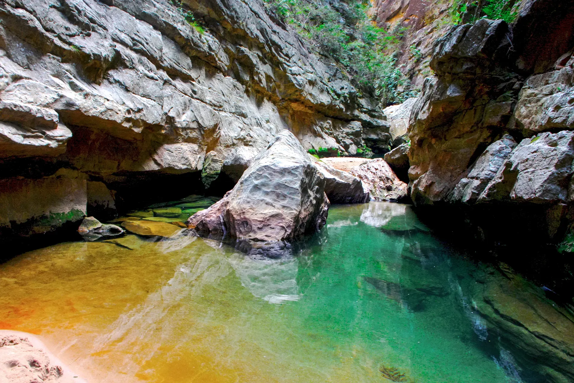 Narrow sandstone canyon with blue-green water flowing through