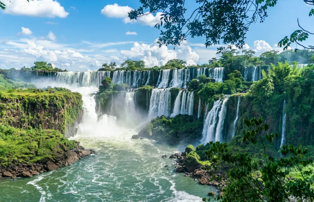 Panoramic view of multiple Iguazu Falls Argentina cascades plunging over lush green cliffs