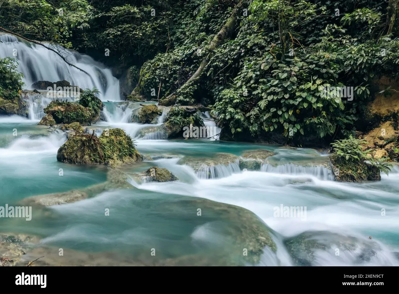 Piala waterfall cascading through lush greenery and mossy rocks
