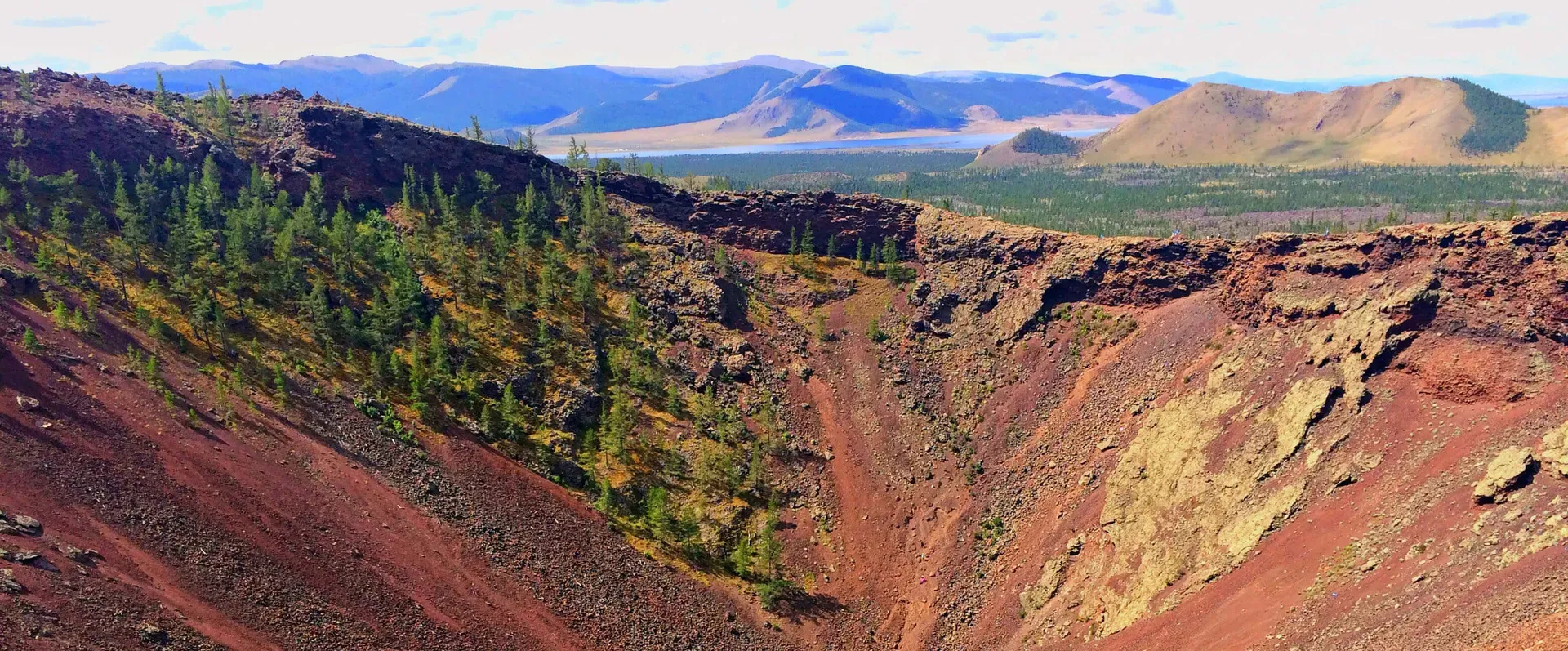 Reddish brown volcanic crater of Khorgo in Mongolia with sparse trees