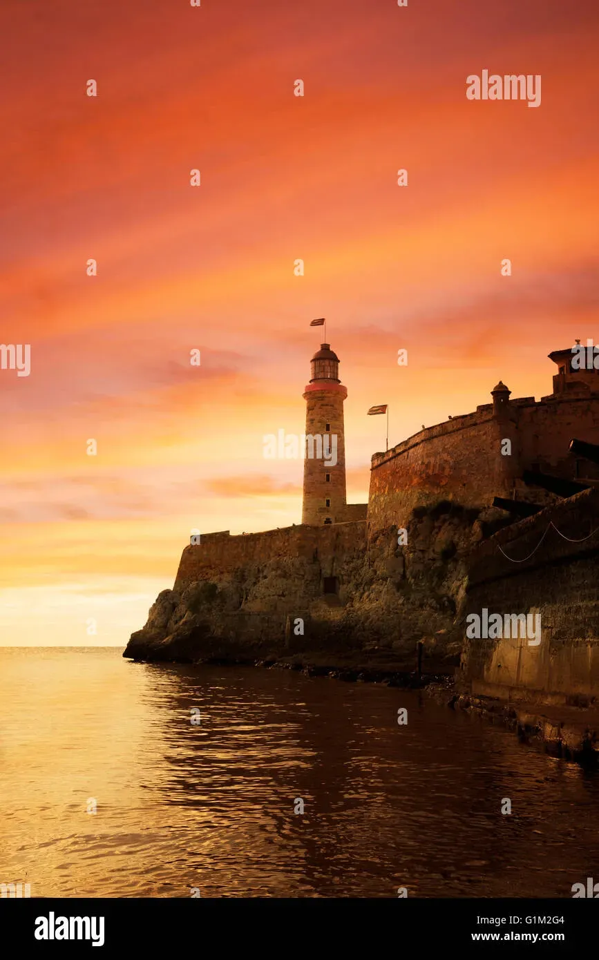 Sunset silhouette of El Morro fortress lighthouse in Havana Cuba with warm orange and purple sky