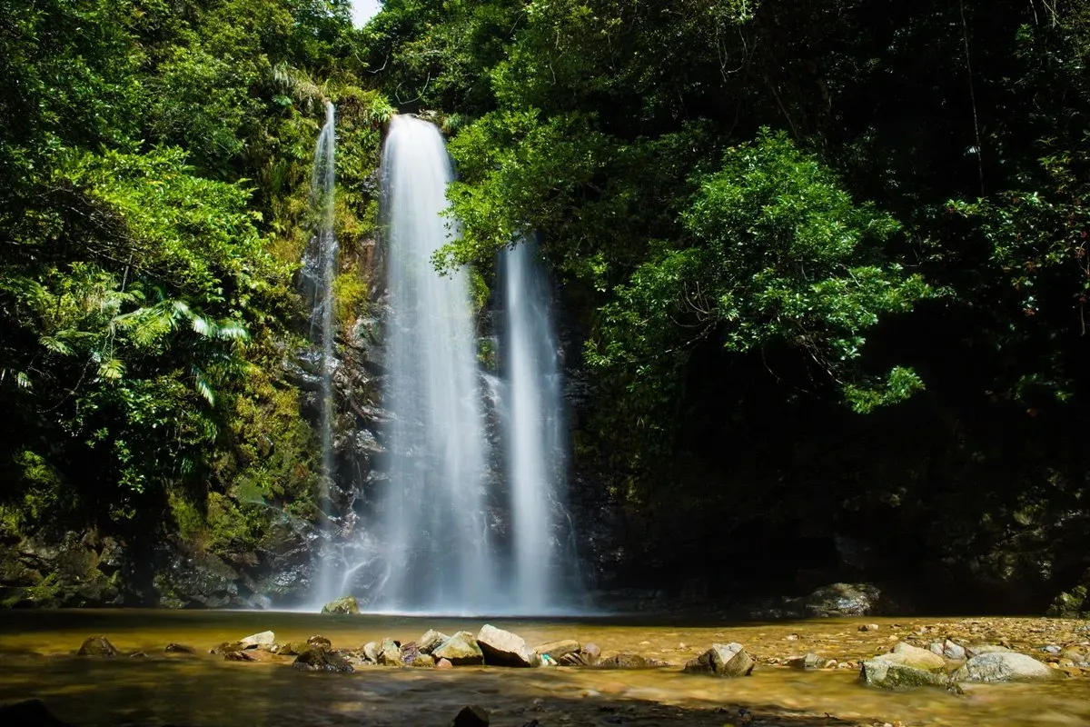 Tall slender Taataki Waterfall cascading into rocky pool in Okinawa Japan