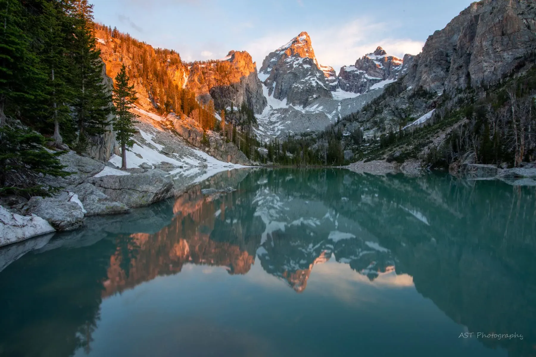 Turquoise alpine lake reflecting jagged snow-capped peaks of the Teton Range