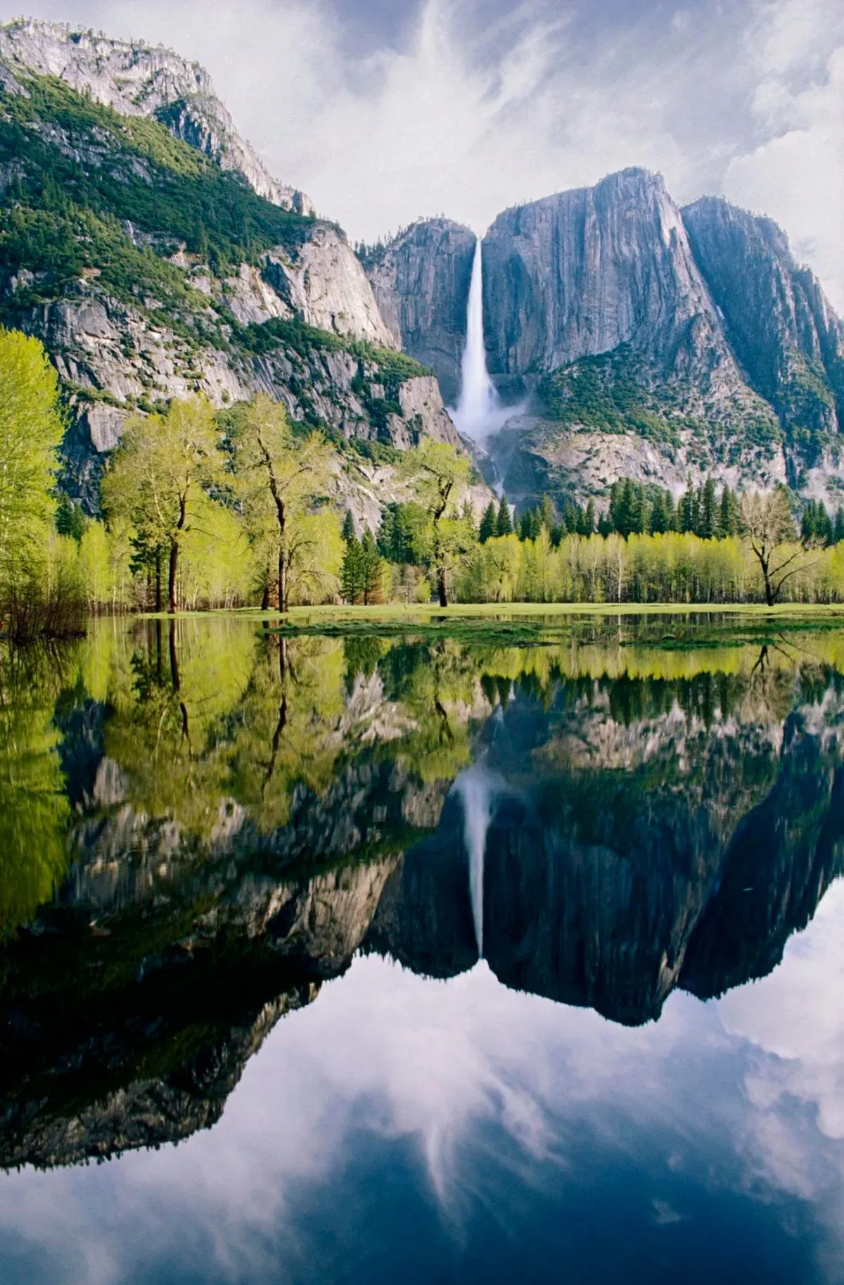 Waterfall descending between granite cliffs with green trees