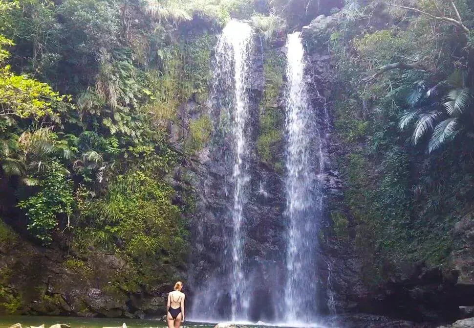Hiker gazing up at the twin cascades of Tadake Falls