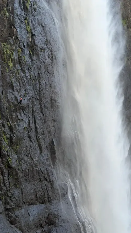 An abseiler descends the 204-metre rope alongside Maletsunyane Falls Lesotho wearing a red helmet