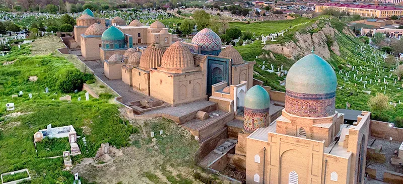 Aerial perspective of Shah-i-Zinda necropolis showing colorful domes amid greenery