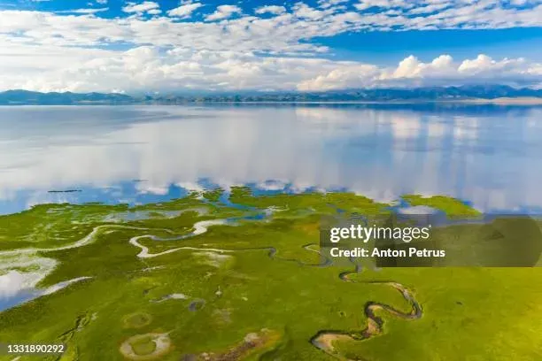 Aerial view of Song Kol Lake Kyrgyzstan with turquoise water ringed by summer pastures and Tian Shan peaks