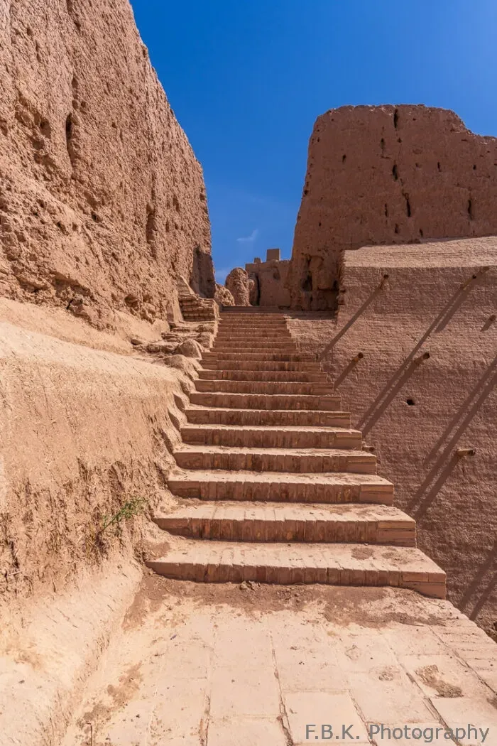 Ancient weathered brick stairs leading up between mud-brick fortress walls at Ayaz Kala in Uzbekistan