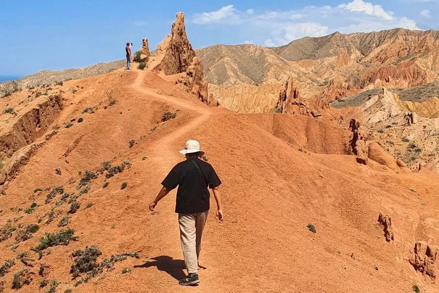 Layered red sandstone cliffs with orange and yellow mineral bands in Skazka Canyon Kyrgyzstan