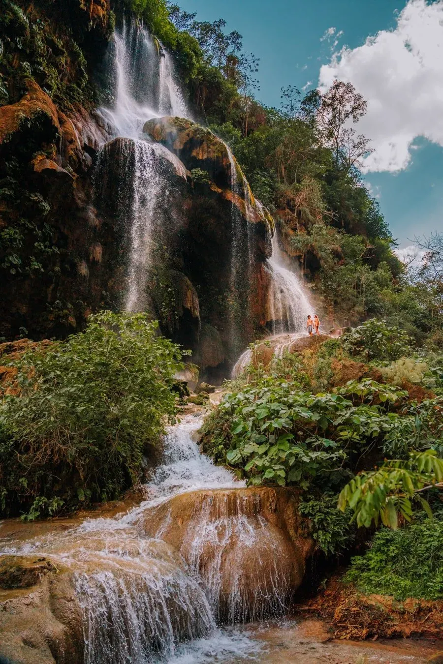 Couple standing beneath the powerful cascading waters of El Aguacero waterfall in the Río La Venta Canyon