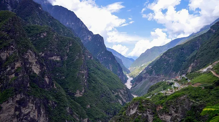 Deep lush green mountain gorge with steep cliffs and winding road in Tiger Leaping Gorge China