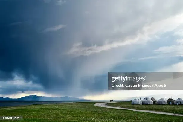 Storm clouds gathering over Song Kol Lake Kyrgyzstan with shifting light across the water and distant mountains