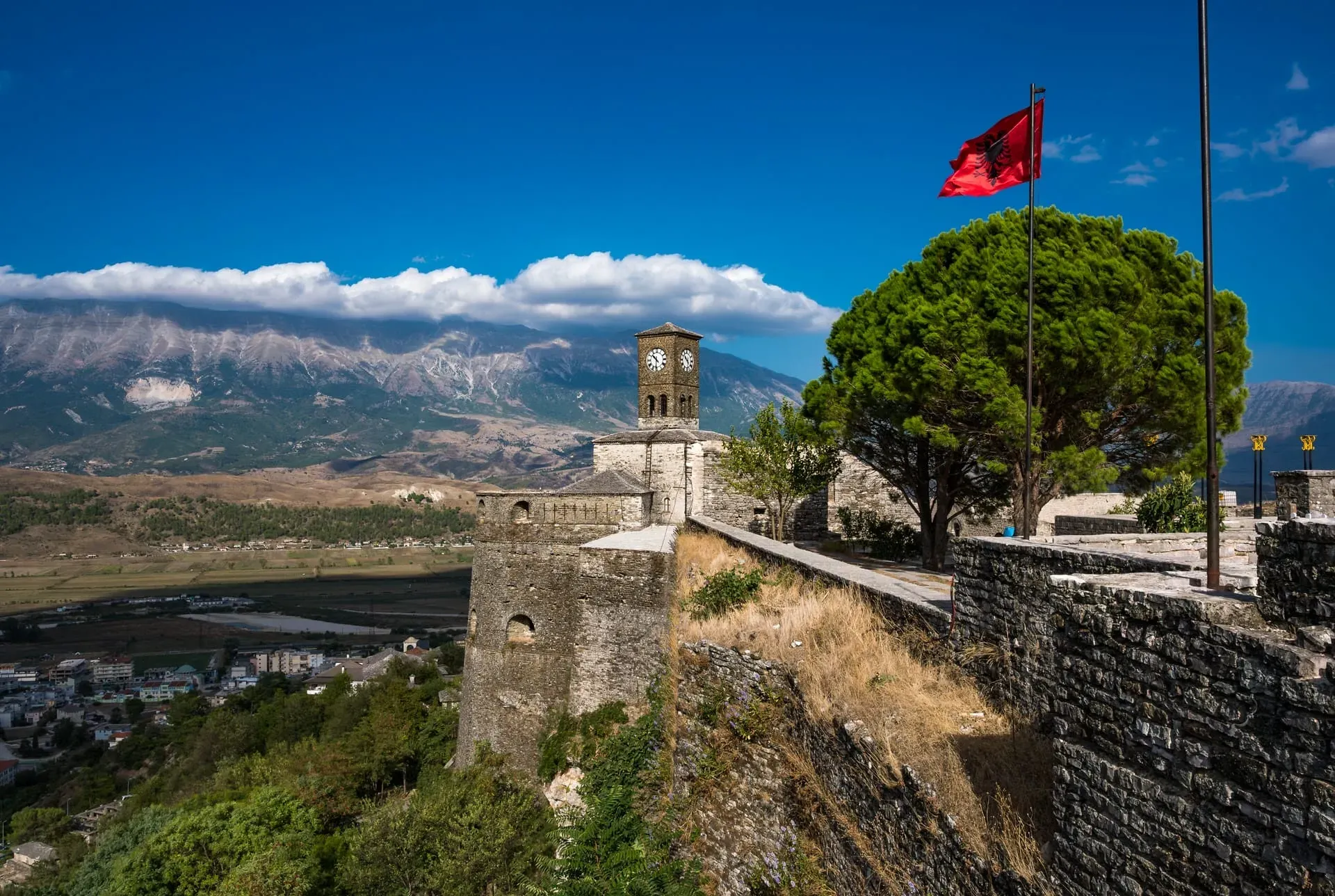 Gjirokastra Castle Albania clock tower with Albanian flag and snow-capped mountains