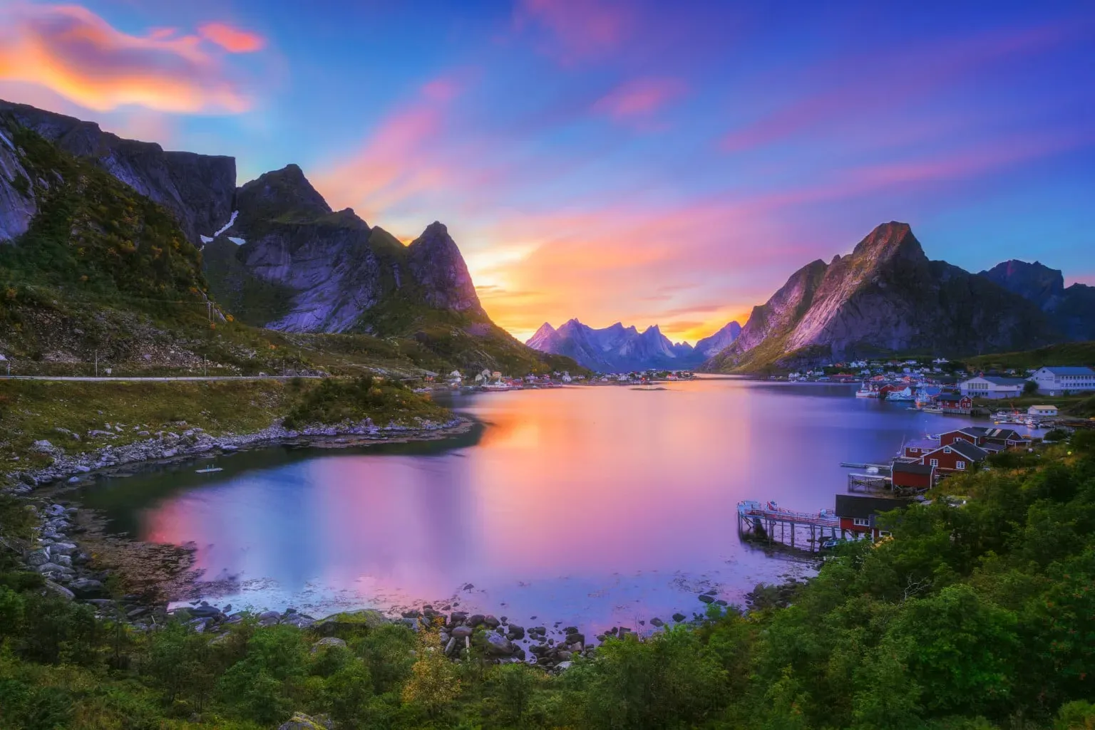 Golden sunset over Reinehalsen viewpoint with Reine village, Reinefjord, and surrounding Lofoten peaks, Norway