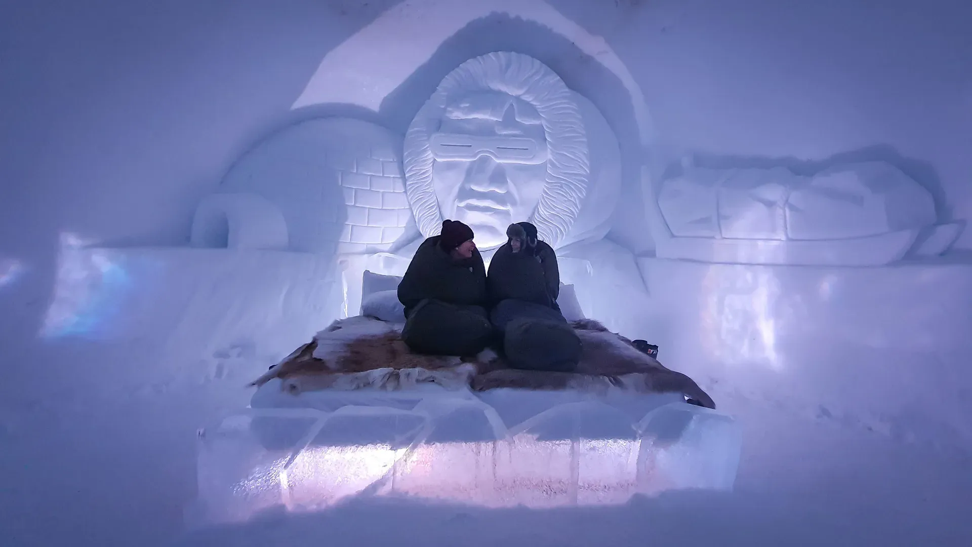 Guests relaxing inside ice dome with carved face sculpture