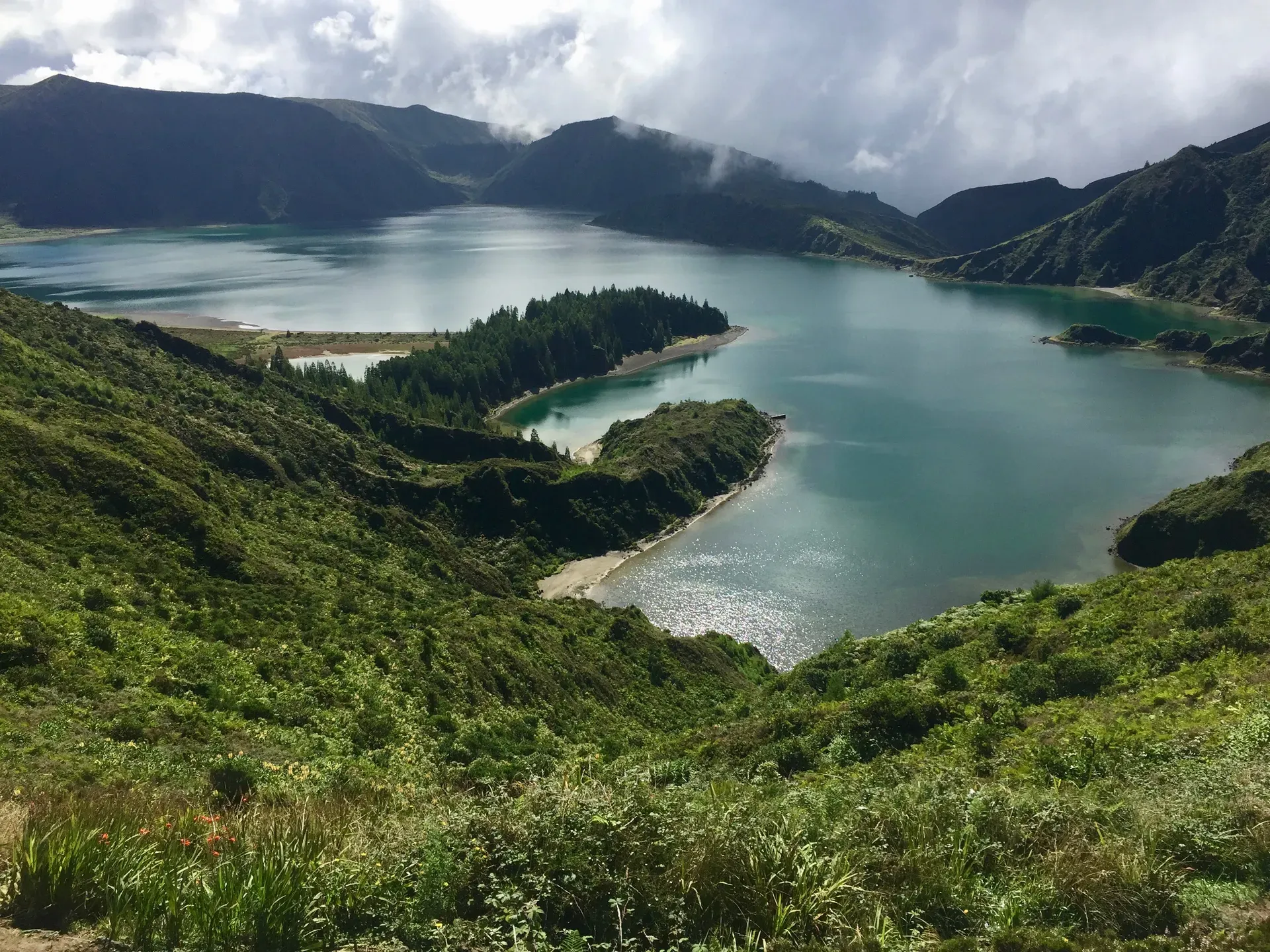 Lagoa do Fogo crater lake surrounded by green hills under cloudy skies in São Miguel, Azores, Portugal