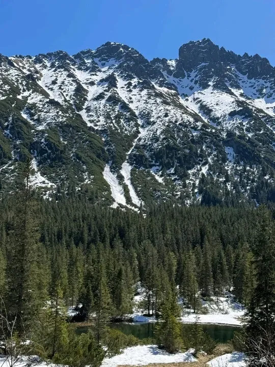 Looking across Morskie Oko lake towards the rugged granite peaks of the High Tatras with partial snow cover