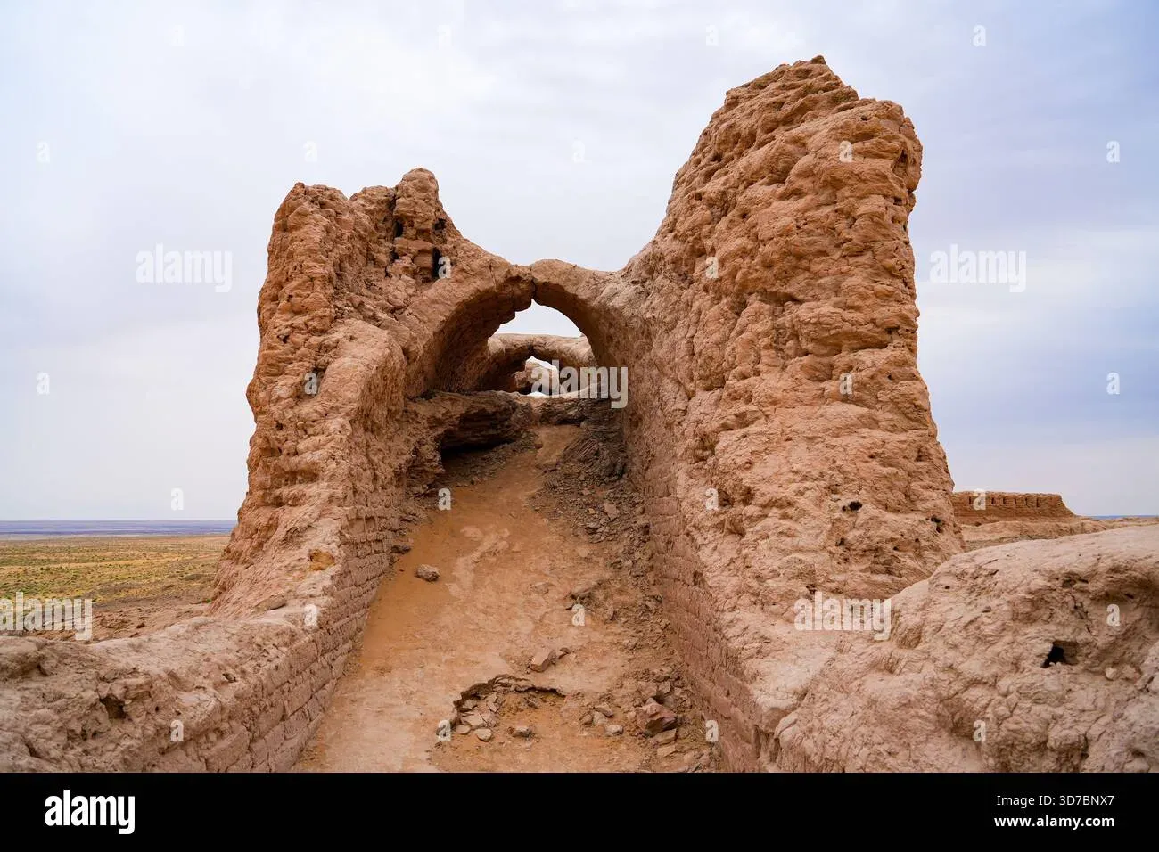 Mud-brick arched passageway and weathered walls of Ayaz Kala fortress in the Kyzylkum Desert, Uzbekistan