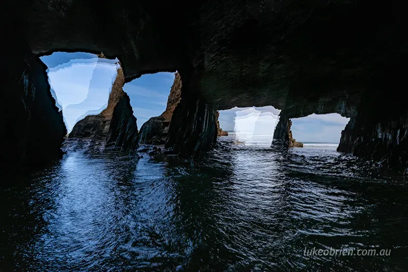Multiple cave openings in Remarkable Cave Tasmania revealing the rocky coastline and bright blue skies