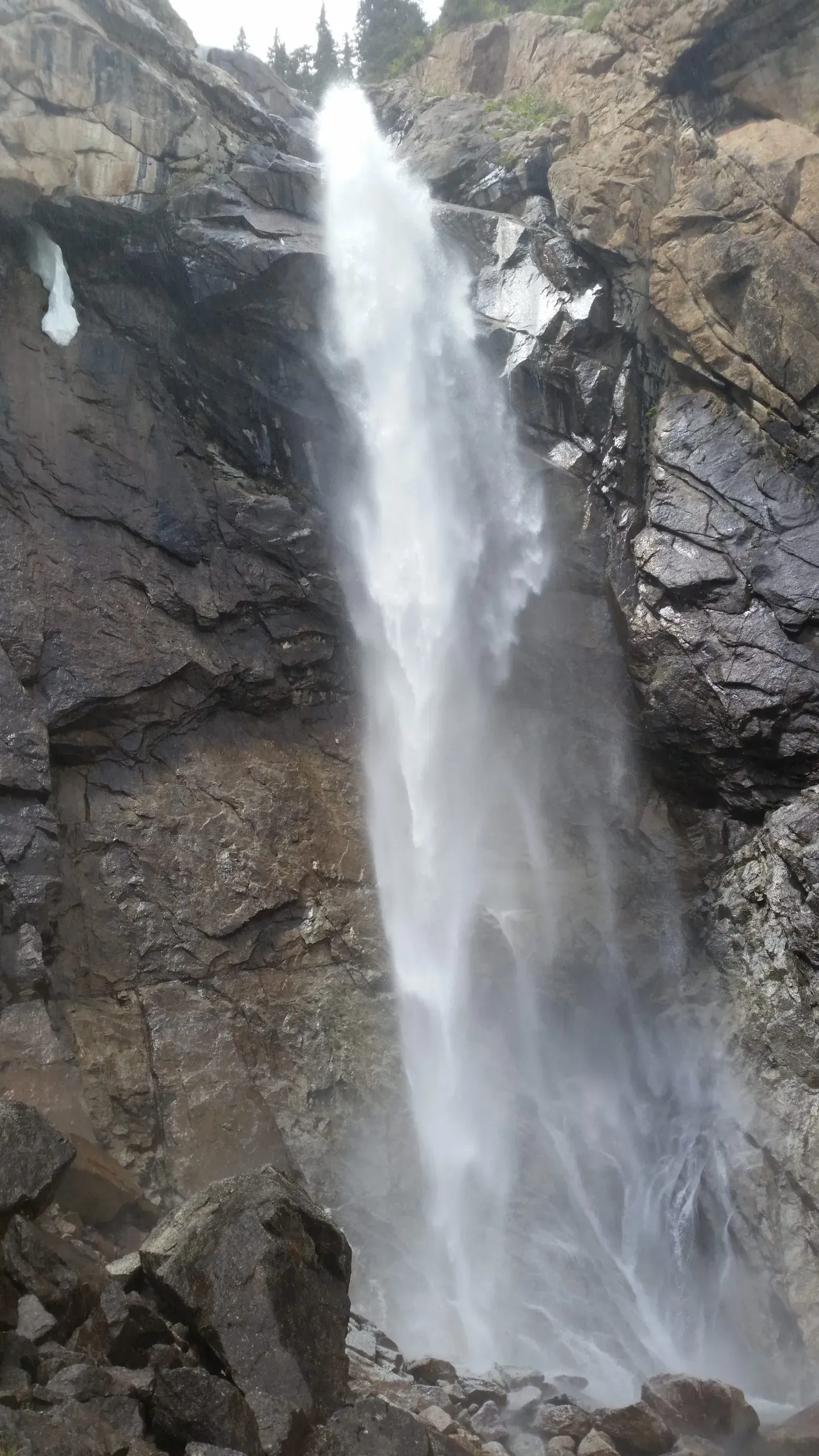 Panoramic view of Barskoon Falls with rugged mountain terrain and cascading water in the Tien Shan mountains