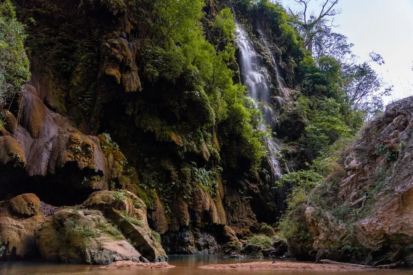 Small secondary waterfalls cascading over mossy rocks along the jungle river path near Cascada El Aguacero