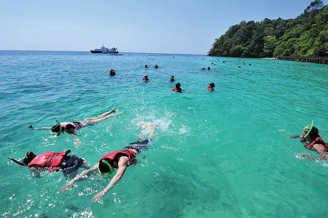 Snorkelers swimming in the clear turquoise waters near the shores of Pulau Payar Marine Park Langkawi