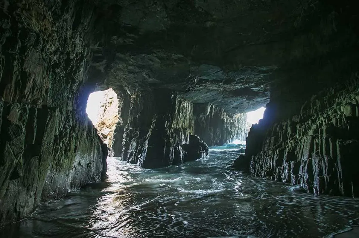 Sunlight streams into Remarkable Cave illuminating rugged dolerite rock walls and shimmering water