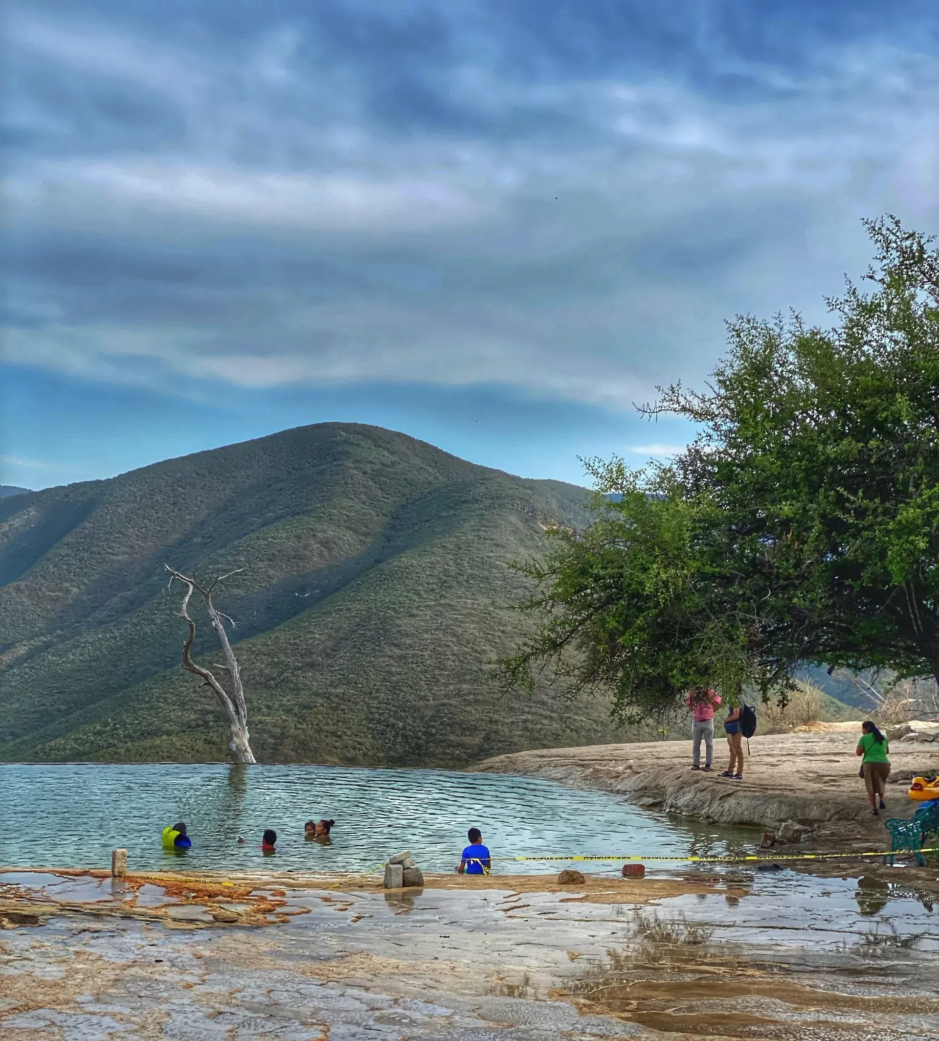Swimmers relaxing in a turquoise mineral pool at Hierve el Agua Oaxaca Mexico with mountain views