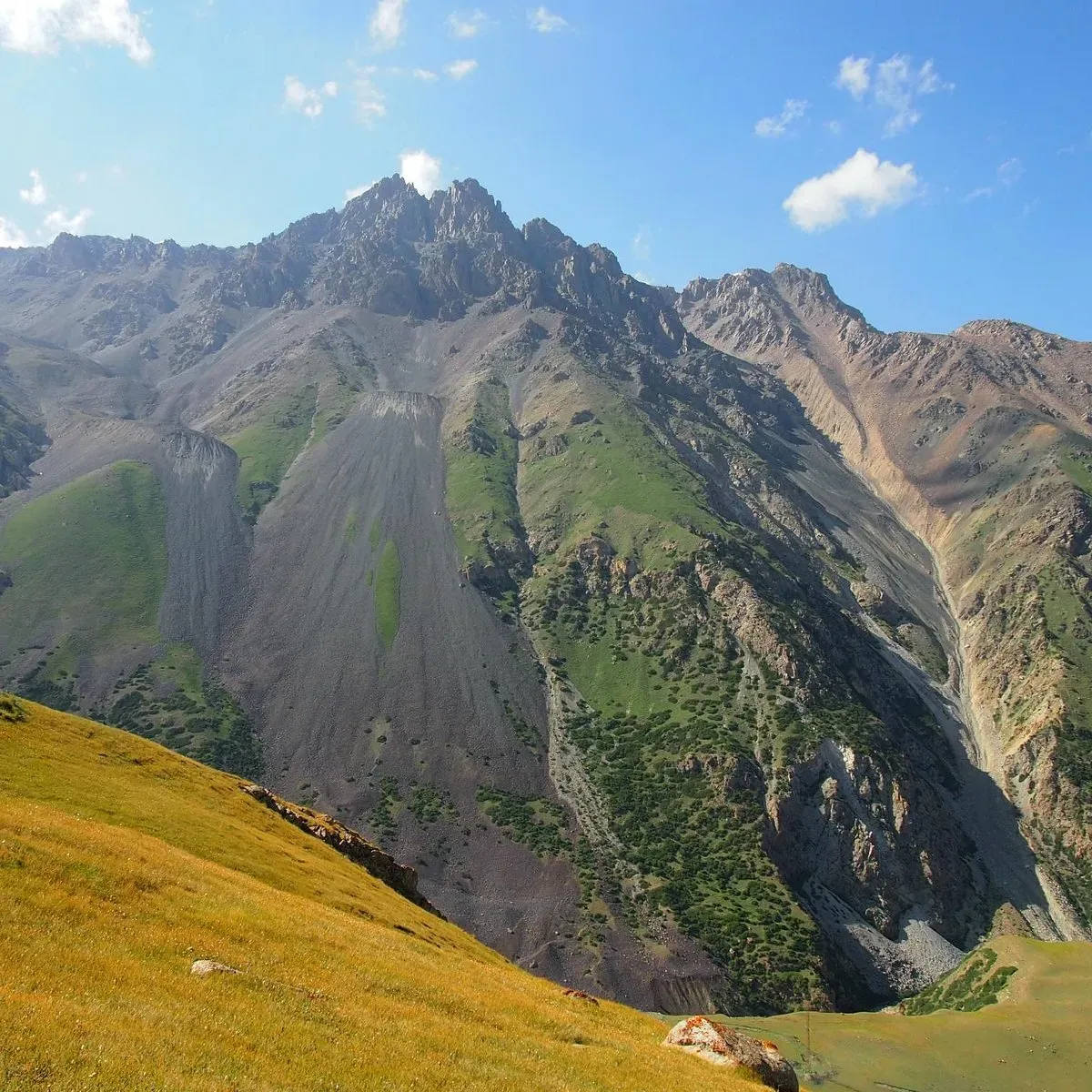 Towering mountain landscape near Barskoon Valley Kyrgyzstan with green slopes and rocky peaks