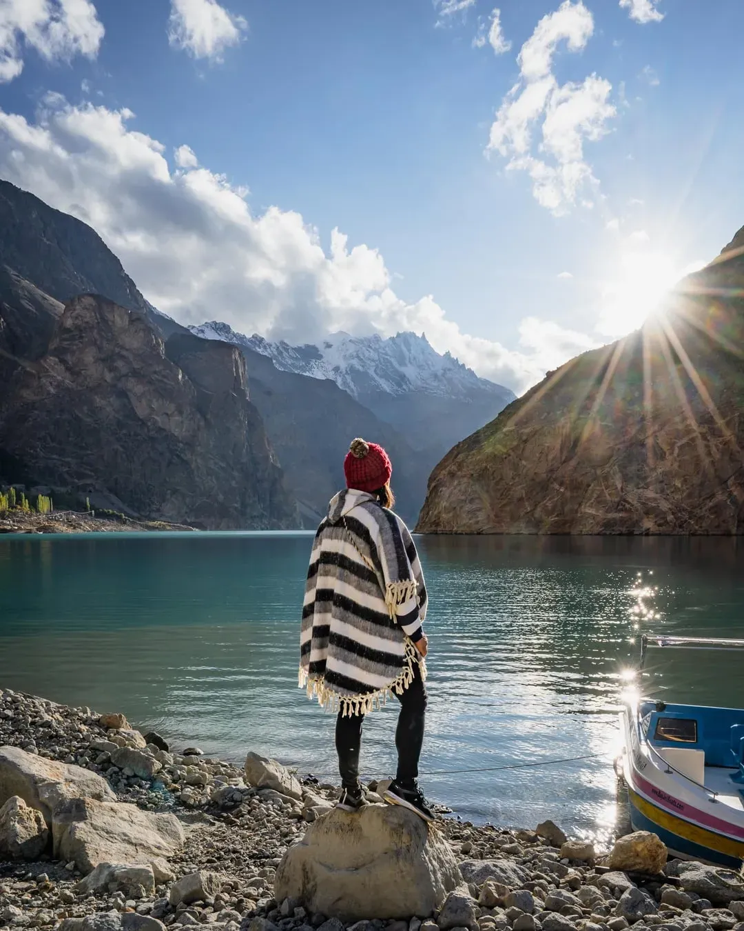 Traveler overlooking Attabad Lake Pakistan with snow-capped Karakoram peaks in background