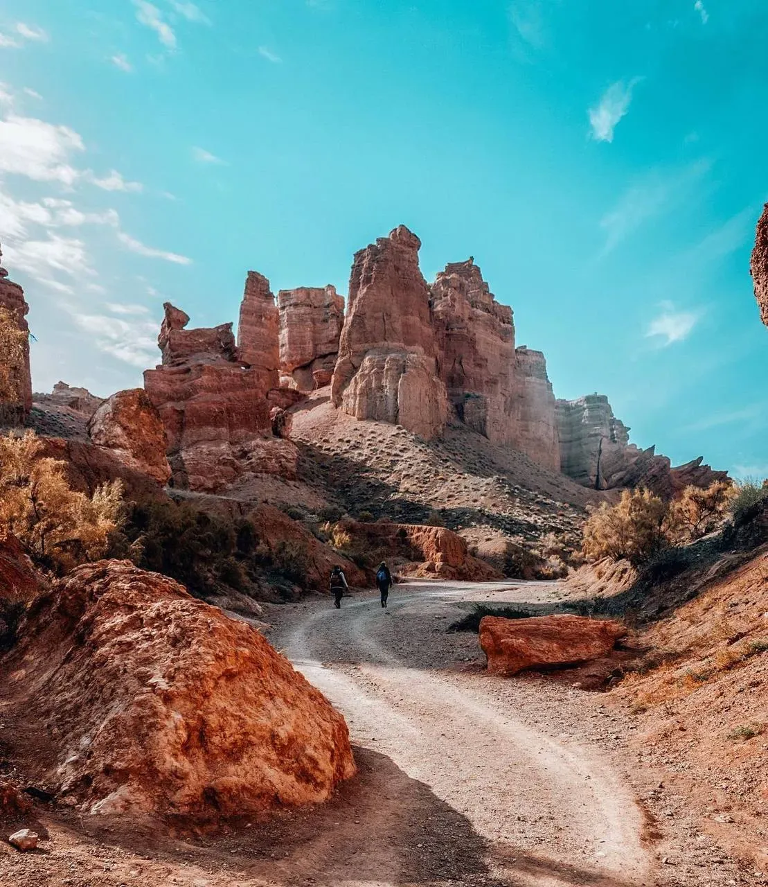 Hikers on winding path toward rock formations in Charyn Canyon Kazakhstan