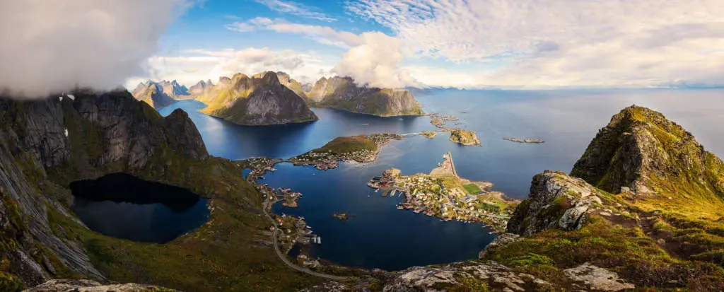 Wide-angle panoramic view of Reinefjord and coastal village from Reinebringen in Lofoten, Norway