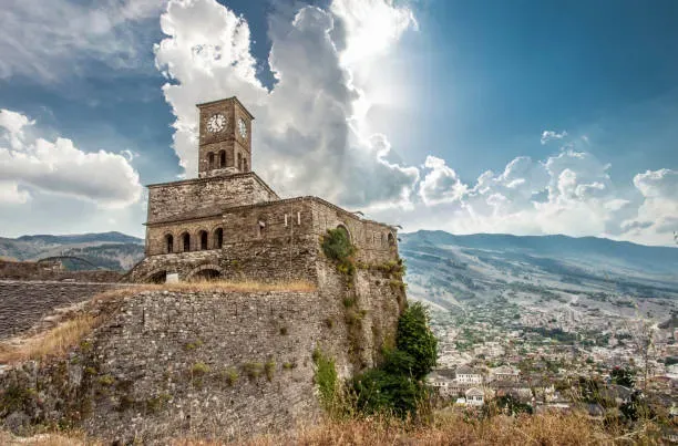 Wide landscape of Gjirokastra Castle Albania with clock tower overlooking the town and mountains