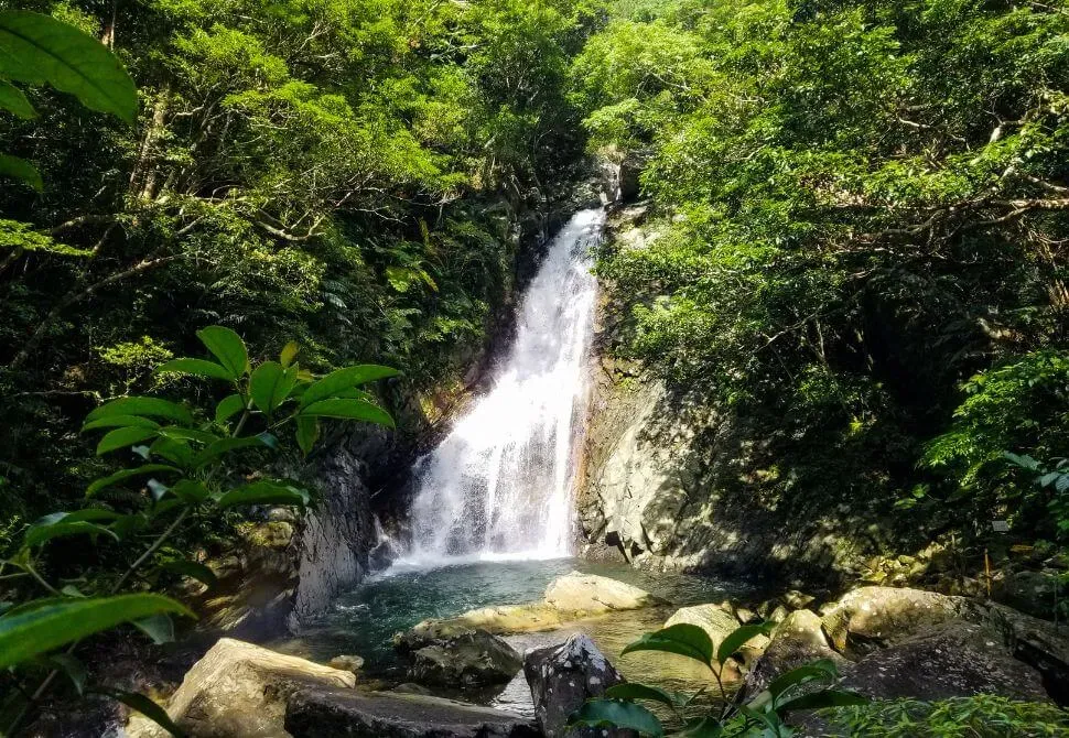 Wide view of Hiji Falls with water streaming down dark rock face