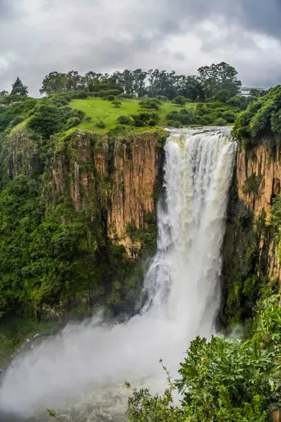 Powerful Howick Falls South Africa cascade on the Umgeni River in KwaZulu-Natal Midlands under cloudy sky